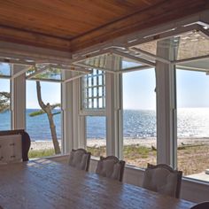 a dining room table and chairs in front of large windows overlooking the beach with ocean view