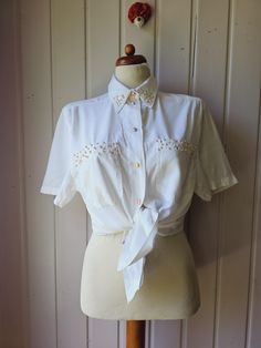 Charming blouse with pearl embroidery in off-white In perfect condition, buttons show some slight signs of wear. 70% Viscose 30% polyester Signed with Gr.38 Seen on a size 38 Laying Flat Dimensions: Shoulder width: 44 cm/ 17.32 inches Armpit-armpit: 51 cm/ 20.07 inch Back length: 68 cm/ 26.77 inch White Short Sleeve Blouse With Button Closure, Cream Short Sleeve Shirt With Button Closure, White Blouse With Button Closure And Short Sleeves, Short Sleeve Embroidered Shirt For Work, Feminine Short Sleeve Shirt With Buttons, Elegant Short Sleeve Shirt With Buttons, Elegant Short Sleeve Blouse With Buttons, Cream Short Sleeve Workwear Shirt, Fitted Collared Tops With Pearl Buttons