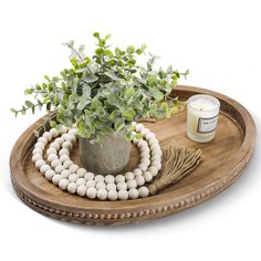 a potted plant sitting on top of a wooden tray next to beads and a candle