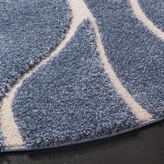 a blue and white area rug on a black surface with an oval design in the middle