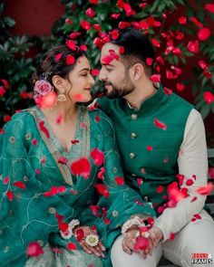 a man and woman sitting next to each other on a bench surrounded by rose petals