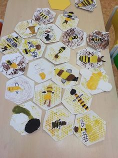 a table topped with lots of paper cut out of honeybees and beehives