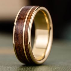 a wooden ring with gold inlays on the outside and inside, sitting on a table