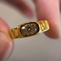 a close up of a person holding a ring with a stone in it's middle