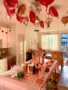 balloons are hanging from the ceiling above a dining room table with red and gold decorations