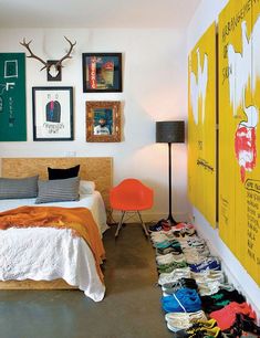 a bed room with a neatly made bed and lots of pictures on the wall above it