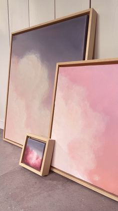 two framed paintings sitting on the floor next to each other