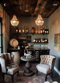 two chairs and a table in a room with wine bottles on the wall behind them