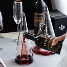 a person pouring wine into two glasses on top of a table with other wines in the background