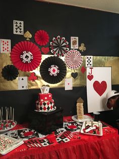 a table topped with cards and cakes on top of a red table cloth