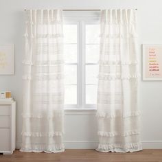 a white curtain with ruffled edges hangs in front of a window next to a dresser