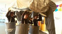 three women standing in front of an elephant statue with buckets on their heads and hands