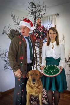 a man and woman standing next to a dog holding a plate with a cake on it