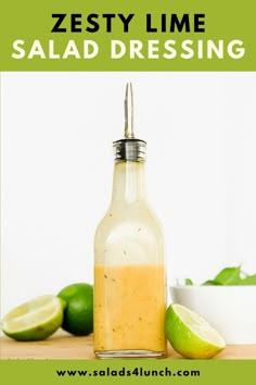 a bottle filled with dressing sitting on top of a wooden table next to limes