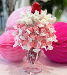 a vase filled with pink and white flowers on top of a table next to paper balls