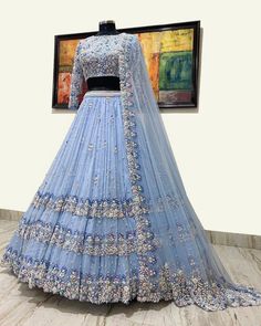 a blue lehenga on display in front of a painting