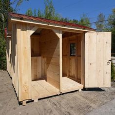 a wooden outhouse sitting on top of a dirt field