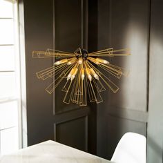 a chandelier hanging from the ceiling in a room with black walls and white chairs