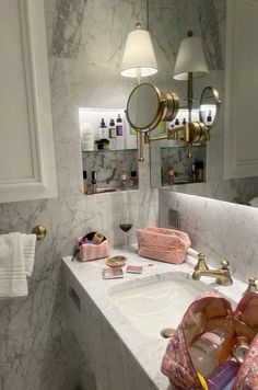 a bathroom with marble counter top and gold faucet lighting above the sink area