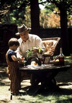 an old man sitting on a chair with a young boy