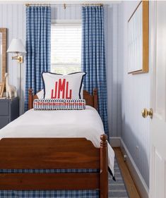 a bedroom with blue and white walls, plaid curtains, and a wooden bed frame