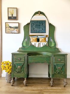 a green dresser with a mirror on top of it and yellow flowers in front of it