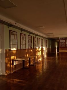 an empty room with tables and benches in the center, sunlight streaming through the windows