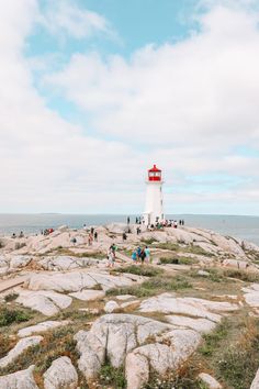 people are standing on rocks near the lighthouse