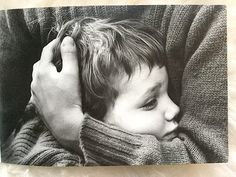 a black and white photo of a young boy holding his mother's arm over her head