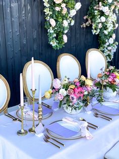 the table is set with plates, silverware and flowers