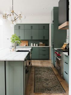 a kitchen with green cabinets and an area rug on the floor in front of it