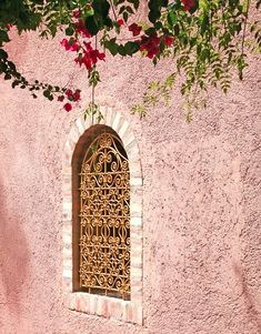 a window on the side of a building with red flowers hanging from it's windowsill