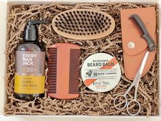 an assortment of men's grooming products in a box with scissors and combs