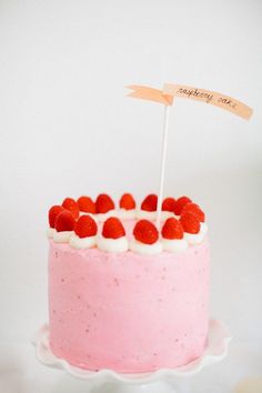 a pink cake with white frosting and strawberries on top