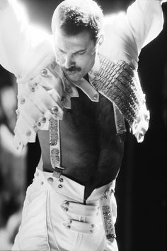 a man dressed in white performing on stage with his arms stretched out to the side