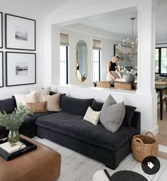 a living room with black couches and pictures on the wall above it, along with a coffee table