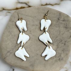 two pairs of white and gold earrings sitting on top of a marble slab