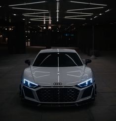 the front end of an audi sports car in a dark parking garage with lights on