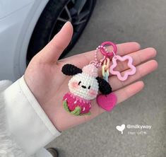 a hand holding a keychain with a small animal on it's thumb