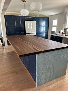 a large kitchen island in the middle of a room with blue cabinets and wood flooring