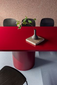 a red table with black chairs and a potted plant