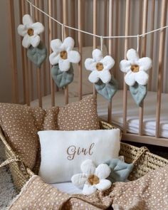 a baby crib with flowers on it and a pillow that says girl next to the crib