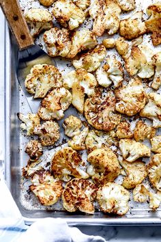 roasted cauliflower on a baking sheet with a wooden spoon