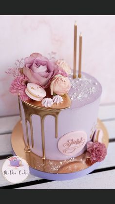 there is a purple cake with flowers on the top and gold trimmings around it