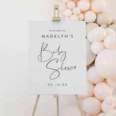 a welcome sign with balloons in the background and a baby shower sign on an easel