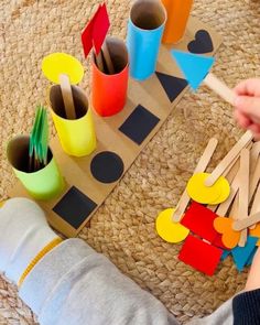 a child is playing with construction paper and wooden pegs on the floor in front of them