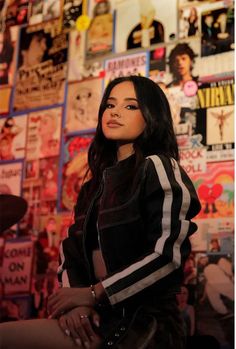 a woman standing in front of a wall covered with posters