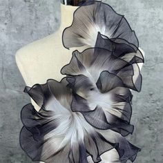 a mannequin with black and white flowers on it's back end, in front of a gray wall