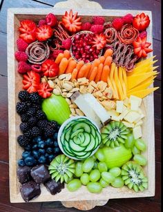 an assortment of fruits and vegetables arranged in a wooden tray on top of a table