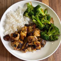 a white plate topped with chicken and broccoli next to rice on top of a wooden table